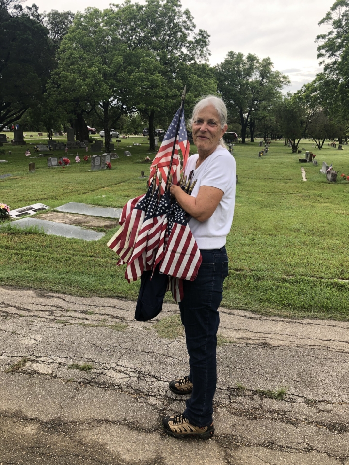VFW Post Auxiliary member Anne Pfannenstiel placing flags on graves of fallen service members. 